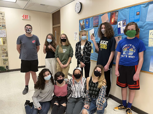 Several members stand in front of the Cymbals bulletin board outside A202 and A203.  (Top to bottom, left to right: Ryan OShaughnessy, Naia Beck, Catherine Donnelly, Emma Granshaw, Dylan Burnham-Clasen, Andrew Wicks, Anna Marino, Stephanie Tortora, Chloe Schiff, Michaela Santulli) 